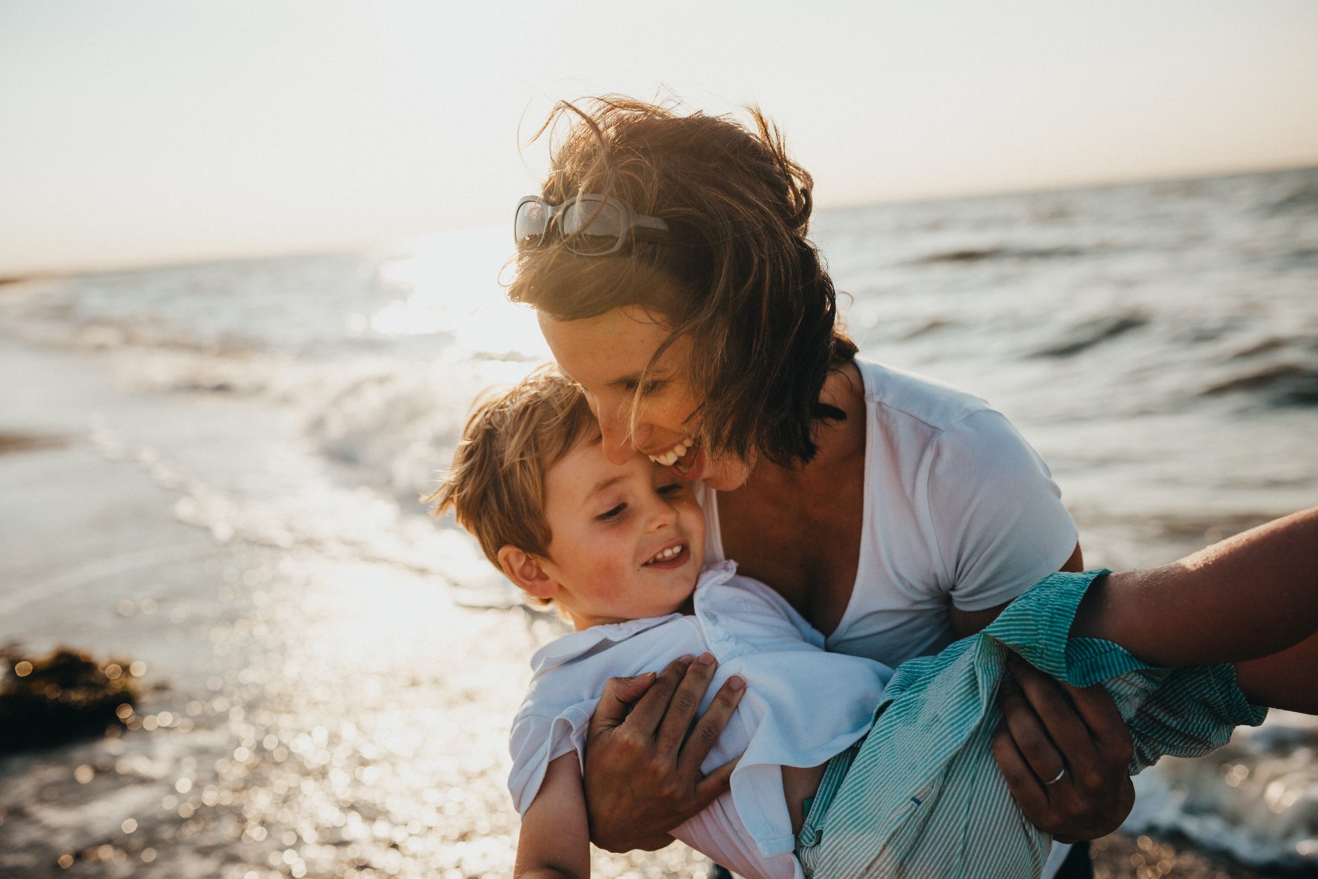 woman-smiling-and-happy-carrying-her-son-at-the-beach